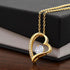 The Forever Love Necklace by ShineOn Fulfillment, adorned with a heart-shaped pendant featuring a central gemstone and CZ crystals along one side, gracefully hangs from a gold chain. Its radiant allure is beautifully set off against the black and white box, making it an ideal choice for any occasion.