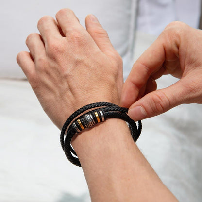 A person adjusts the Love You Forever Bracelet by Divine Dispatch, crafted from black vegan leather with metallic accents, on their wrist.